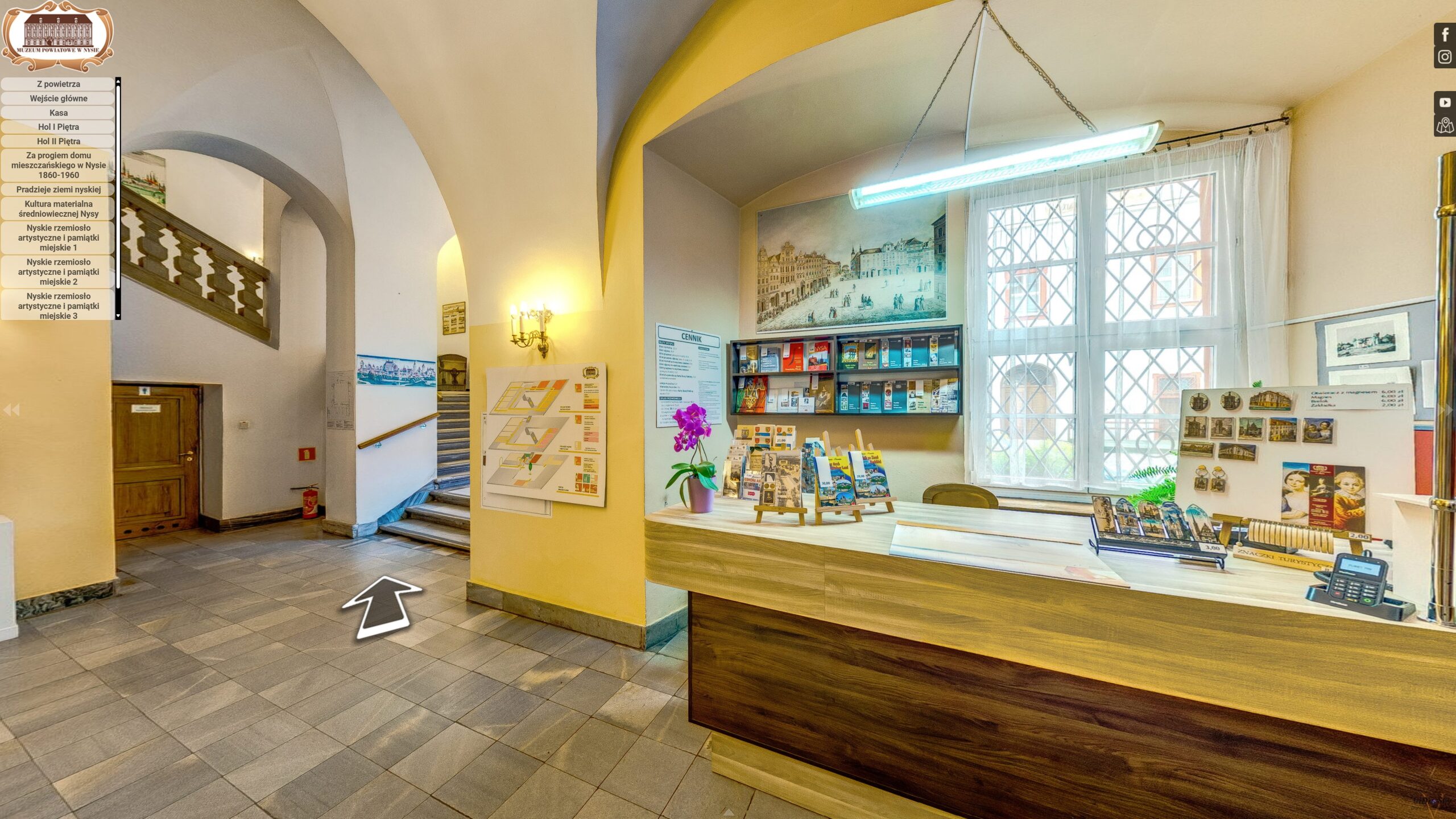 Wnętrze wejścia do Muzeum Powiatowego w Nysie, przedstawiające recepcję, kasę biletową oraz plan muzeum, widoczne w wirtualnym spacerze 360.